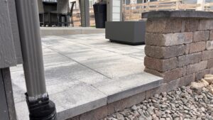 Backyard patio with large stone tiles, brick wall.