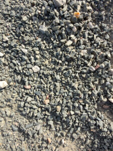 Close-up of ground covered with small irregular gray gravel stones and scattered lighter rocks